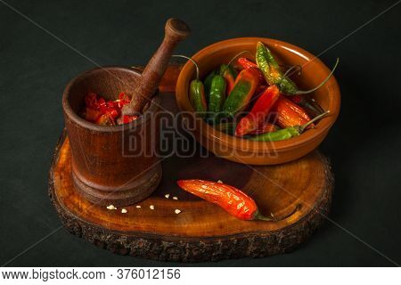 Still Life Of Hot Peppers In A Mortar Next To A Bowl On A Dark Background