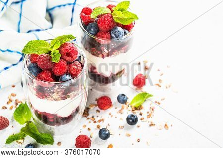 Parfait With Granola, Jam And Fresh Berries In The Glass Jar At White Table. Close Up. Healthy Desse