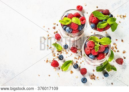 Parfait With Granola, Jam And Fresh Berries In The Glass Jar At White Table. Top View With Copy Spac