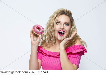 Food Concepts. Cute And Funny  Caucasian Blond Girl With Pink Doughnut In Hands. Posing With Excited