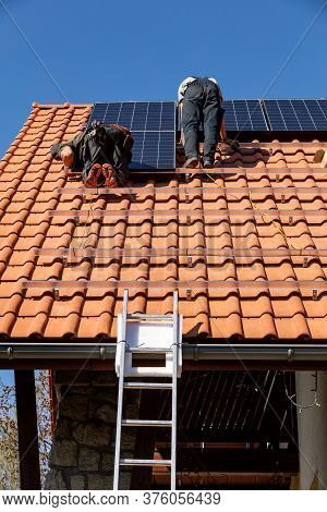 Ochojno, Poland - April 8, 2020: Workers Installing Solar Electric Panels On A House Roof In  Ochojn