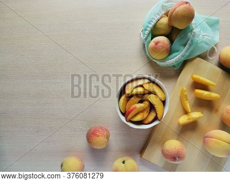 Juicy Sliced Peaches In A Plate, Next To Whole Peaches In A Reusable Bag, Photo With Copy Space