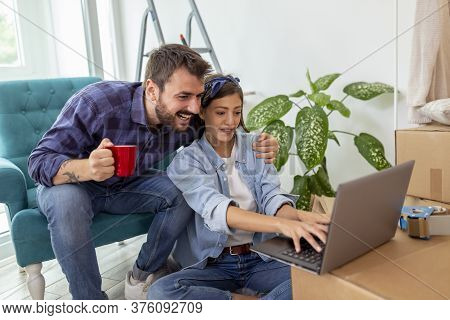 Beautiful Young Couple In Love Moving In Together, Surfing The Net On Laptop Computer, Searching The