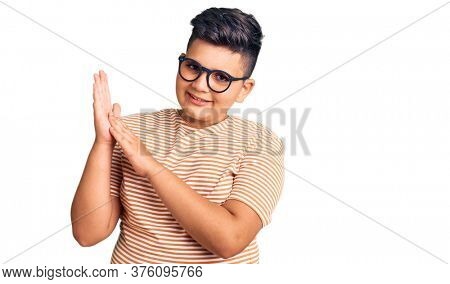 Little boy kid wearing casual clothes and glasses clapping and applauding happy and joyful, smiling proud hands together 