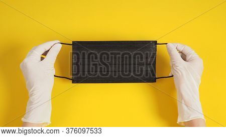 Two Hand With Latex Gloves And Black Face Mask On Yellow Background.