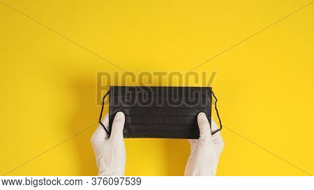 Two Hand With Latex Gloves And Black Face Mask On Yellow Background.