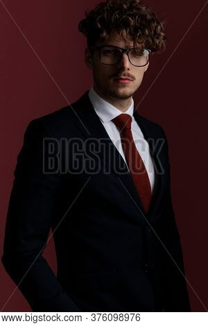 dramatic portrait of an young handsome businessman with a serious look on his face posing on pink studio background