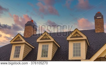 Three Dormers And Two Chimneys On Residential Roof