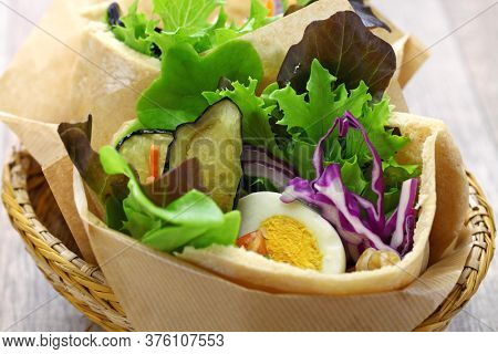sabich: israeli pita sandwich with fried eggplant, hard boiled egg, israeli salad, amba and tahini sauce