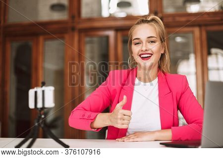 Beautiful Smiling Girl In Pink Jacket Happily Looking In Camera Showing Thumb Up While Recording New