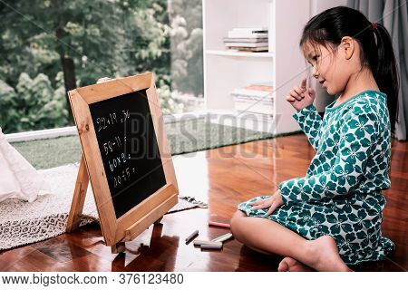 An Asain Girl, 6 Year Old Is Thinking In Caculating Mathermatical Problems On The Blackboard, Concep