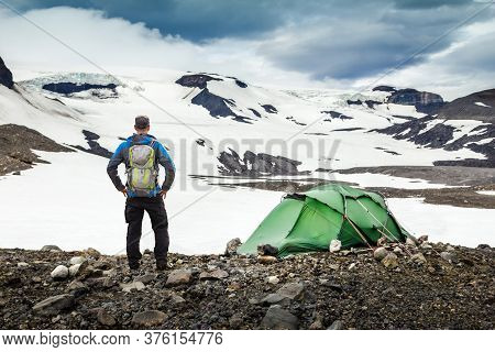 Hiker Man With Backpack And Tent Camping In Snow Mountain Glaciers And Storm Wind. Thorisdalur, Thor
