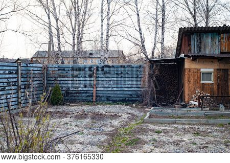 Village Courtyard With An Old Building And An Iron Fence