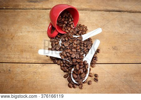 red ceramic cup on a wooden board coffeebeans porcealain spoons