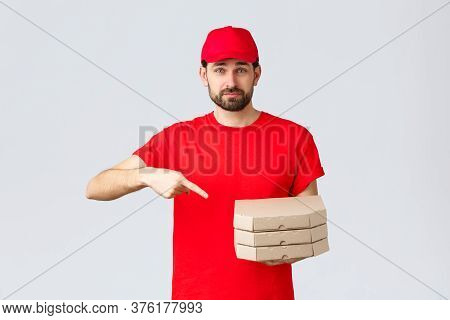 Food Delivery, Quarantine, Stay Home And Order Online Concept. Confident Friendly Courier In Red Uni