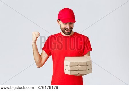 Food Delivery, Quarantine, Stay Home And Order Online Concept. Happy, Excited Bearded Courier In Red