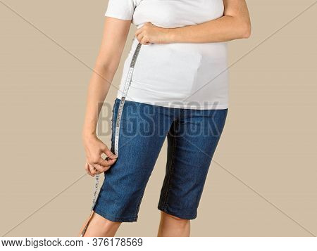 Caucasian Mature Adult Woman Dressed In A White T-shirt And A Blue Denim Capris Is Going To Shorten 