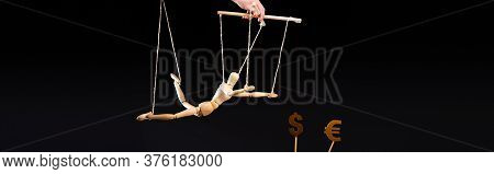 Cropped View Of Puppeteer Holding Wooden Marionette On Strings Near Currency Signs Isolated On Black