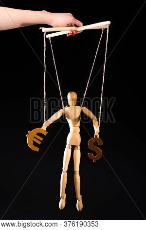 Cropped View Of Puppeteer Holding Wooden Marionette On Strings With Currency Signs Isolated On Black
