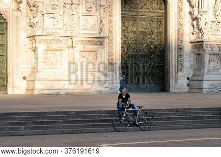 Milan, Italy - May 4, 2020: Bicyclist Sitting On Duomo Square. Italy Enters Second Phase Of Coronavi