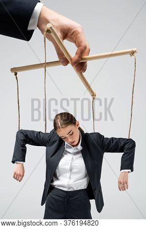Cropped View Of Puppeteer Holding Businesswoman Marionette On Strings Isolated On Grey