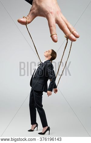 Cropped View Of Puppeteer Holding Businesswoman Marionette On Strings Isolated On Grey