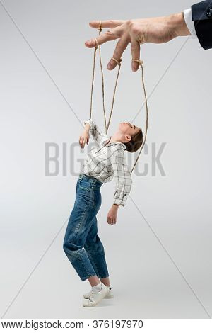 Cropped View Of Puppeteer Holding Marionette On Strings Isolated On Grey