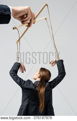 Cropped View Of Puppeteer Holding Businesswoman Marionette On Strings Isolated On Grey