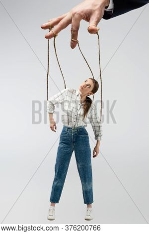 Cropped View Of Puppeteer Holding Marionette On Strings Isolated On Grey
