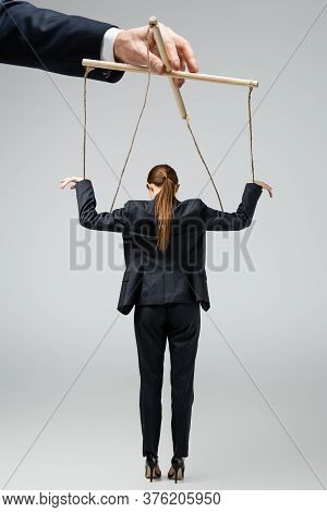 Cropped View Of Puppeteer Holding Businesswoman Marionette On Strings Isolated On Grey