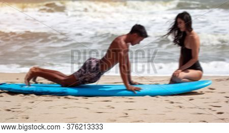 Blur Motion Of Young Handsome Man Teaching Beauty Lady For Basic Patter Of Surfing,on The Beach