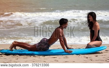 Blur Motion Of Young Handsome Man Teaching Beauty Lady For Basic Patter Of Surfing,on The Beach