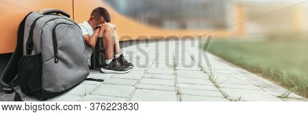 child with backpack in depression is sitting on the floor doesn't want back to school