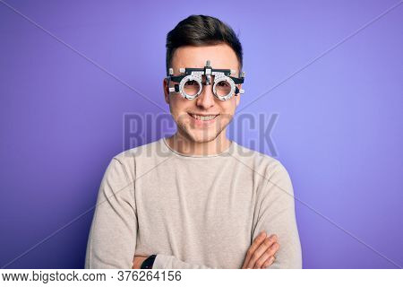 Young handsome caucasian man wearing optometrical glasses over purple background happy face smiling with crossed arms looking at the camera. Positive person.