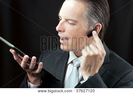 Businessman Using Tablet Adjusting Headset Earpiece.