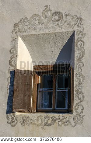 Old Wooden Window With Floral Decorations On The White Wall In The Ancient Village Of Guarda, Scuol 