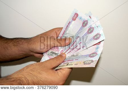 Uae National Currency. Uae Money Banknotes. Young Man Holds In His Hands Dirhams On Light White Back