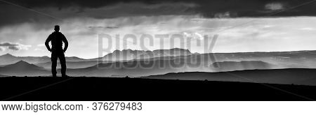 Monochrome Hiking Man Silhouette Enjoying Amazing Sunset Mountains. Fantastic Panorama Of Misty And 