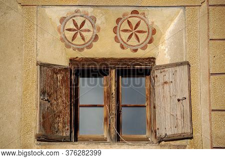 Old Wooden Window On A Wall With Decorations In The Ancient Village Of Guarda, Scuol Municipality, E
