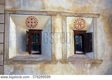 Two Old Wooden Windows On A Wall With Decorations In The Ancient Village Of Guarda, Scuol Municipali