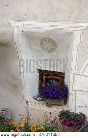 Small Window And Flowers In The Ancient Village Of Guarda, Scuol Municipality, Engadin Valley, Graub