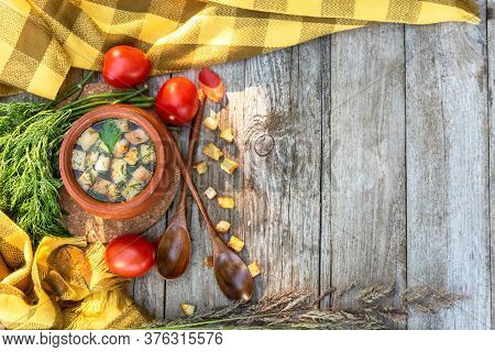 Autumn Transparent Broth With Croutons And Dill In A Clay Pot With Tomatoes Lying Next To It, A Bunc
