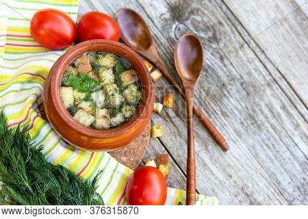 Autumn Transparent Broth With Croutons And Dill In A Clay Pot With Tomatoes Lying Next To It, A Bunc
