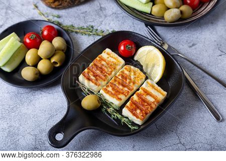 Grilled Haloumi Cheese On A Black Pan With Olives, Tomatoes, Cucumbers And Pepperoni. Close-up.