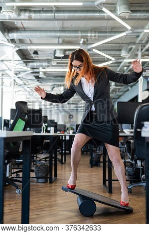 A Woman In A Suit Is Engaged On A Rocker-skateboard During A Break At Work. A Female Office Employee