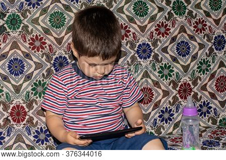 A Little Boy 2-3 Years Old Looks Into The Screen Of The Tablet. Cartoons For Children, Screen Time, 