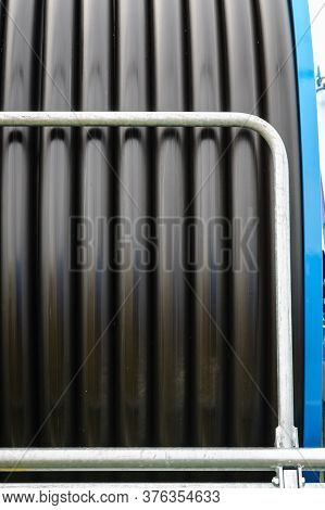 Irrigating With Hose Reel Irrigator. Rolled Up Of Black Rubber Hose, Industrial Detail.