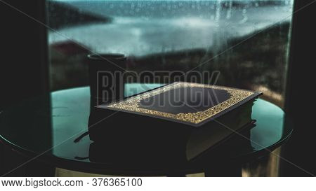 Shot Of An Islamic Book And A Coffee On A Table At A House By The Sea With Beautiful Sea On The Back