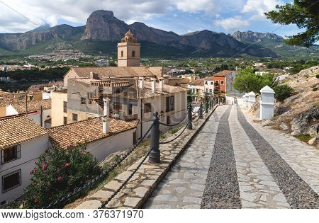 Cobbled Street To Church Of Polop De Marina With Rocky Mountainrange, Costa Blanca, Spain