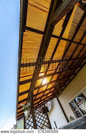 The Roof Of The Veranda Of Orange Polycarbonate On Blue Sky Background.